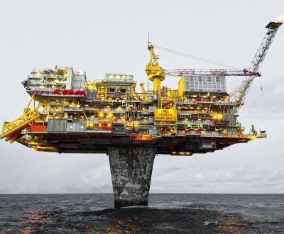 A well-lit offshore oil platform against a cloudy sky in Norway's waters.